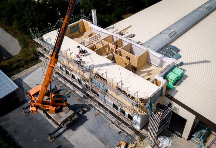 Aufstockung des Firmengebäudes: Holzelemente werden mit dem Kran versetzt