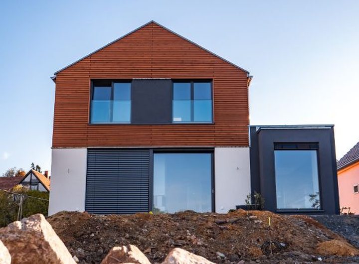 Fertiggestelltes Einfamilienhaus mit Satteldach und roter Holzfassade